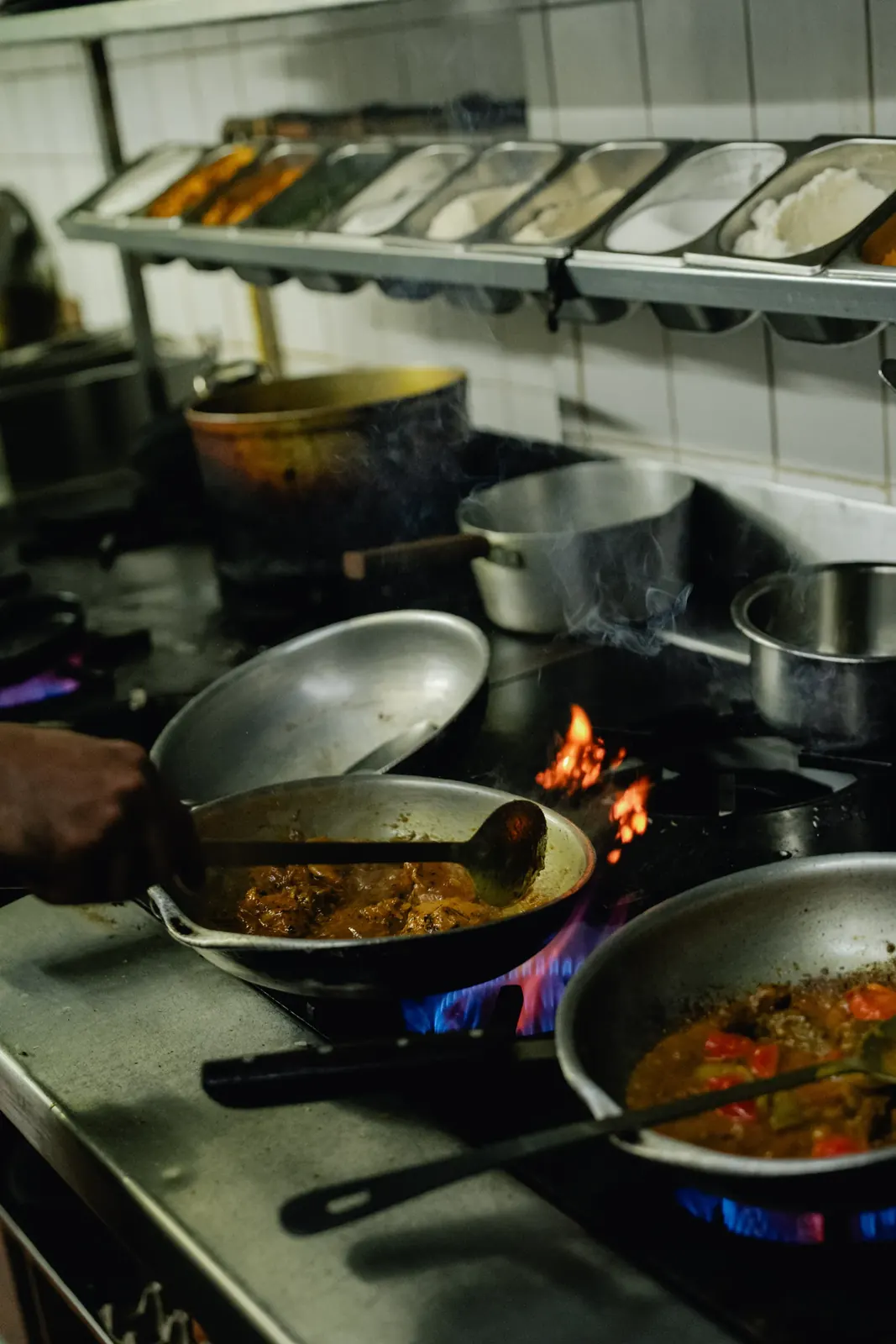 A chef finishing a curry over an open gas flame in the Maharaja of India kitchen