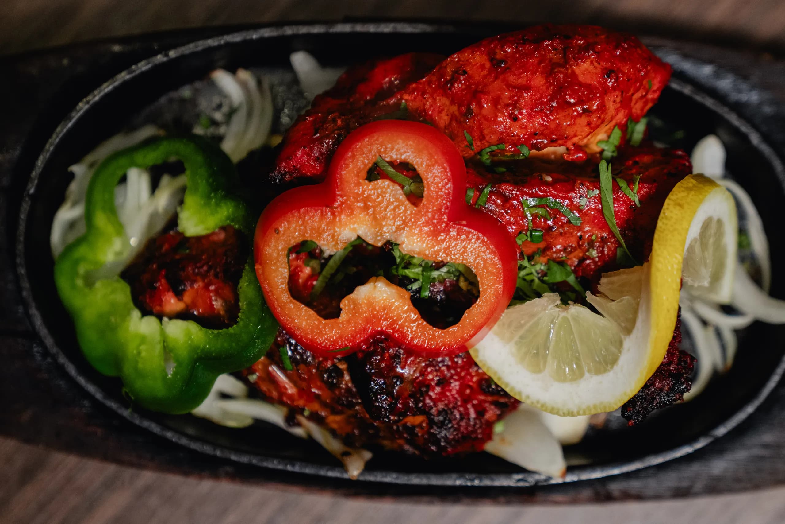 Tandoori mixed grill on a sizzling platter with peppers and lemon