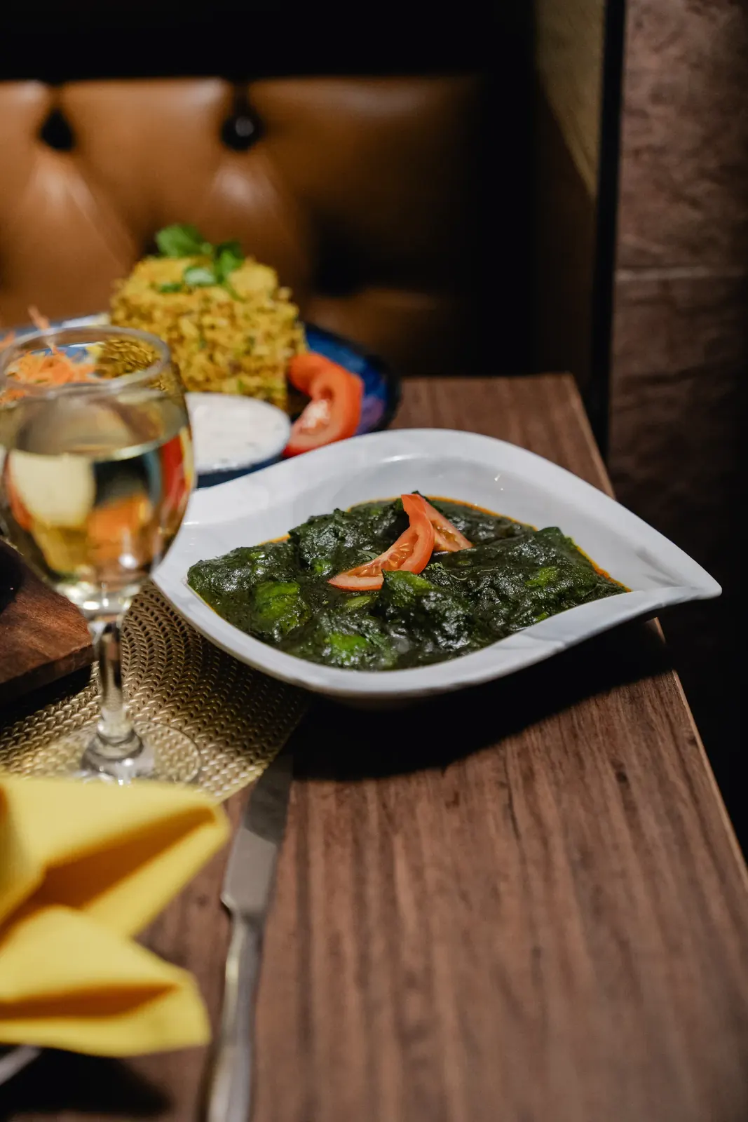 Spinach saag garnished with tomato, served with pilau rice and raita
