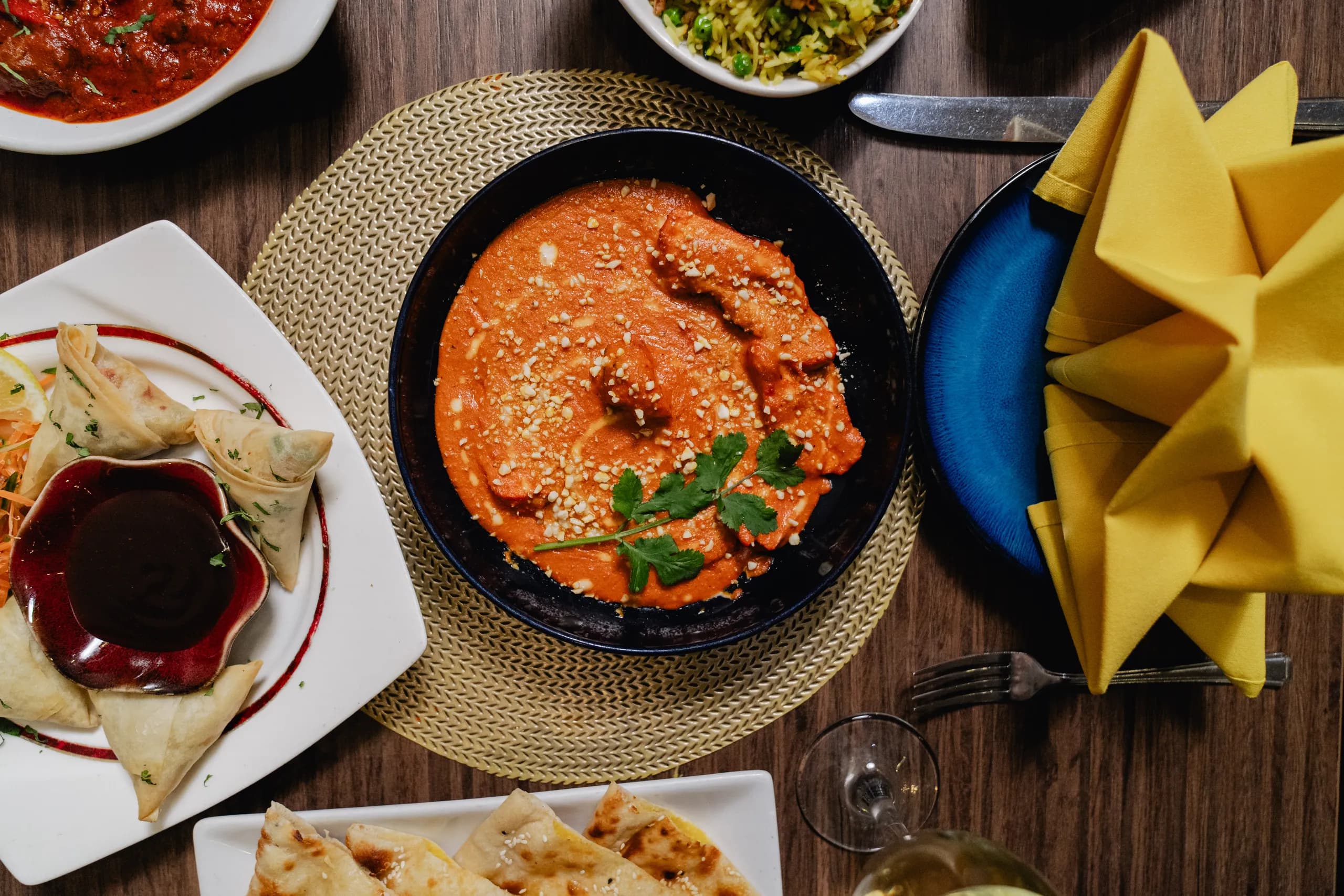 A shared spread of rich Indian dishes served at the table